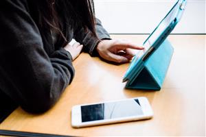 Person using an iPad with a phone next to him/her 